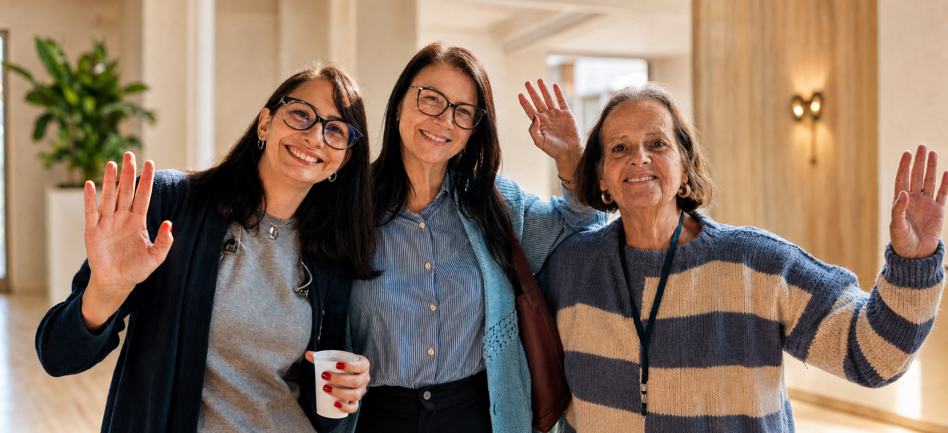 Três mulheres da comunidade Vida Nova sorrindo e acenando